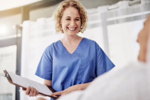 Nurse holding clipboard and speaking with patient 