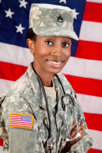 Military member in fatigues in front of flag