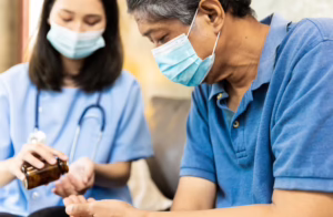 female medical assistant pouring pills into her hand to give to senior man