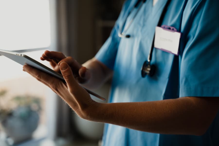 Medical assistant typing information on a tablet