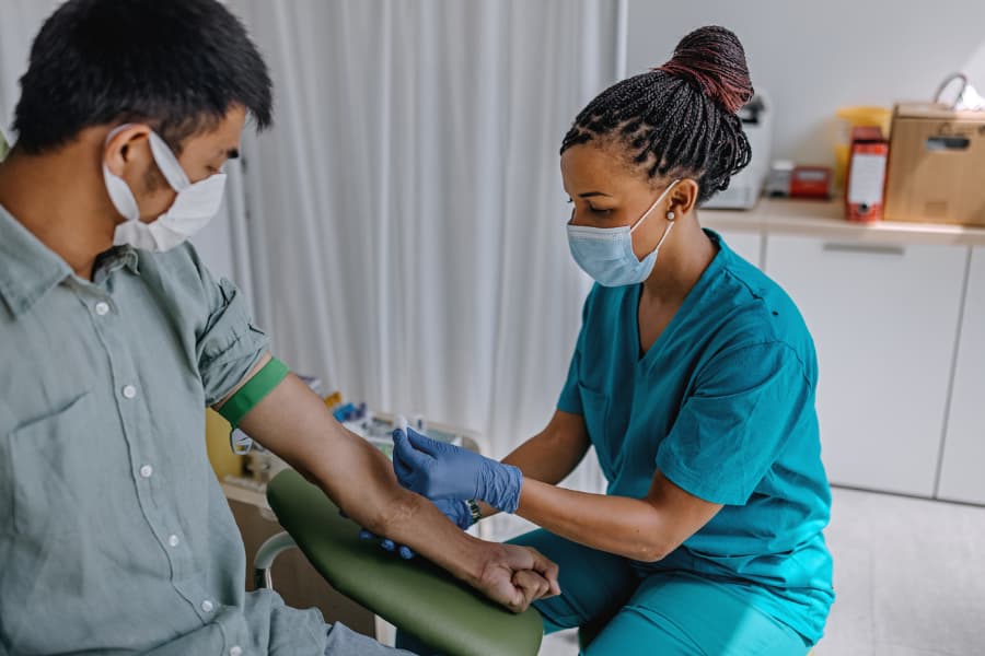 Phlebotomist prepares to draw blood samples from patient