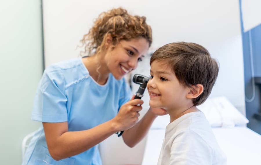 Pediatric medical assistant examining child’s ear