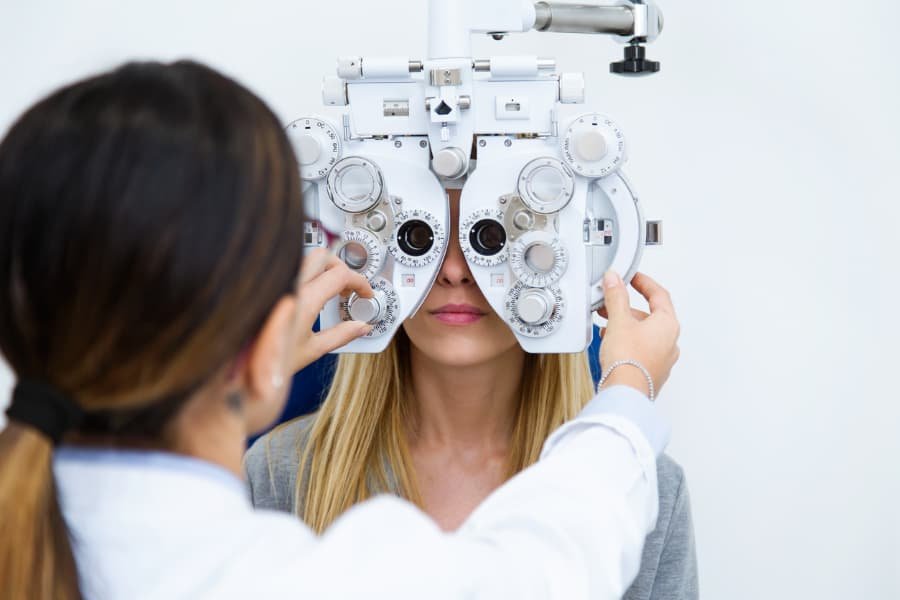 Woman sitting in chair with ophthalmic medical assistant performing eye test