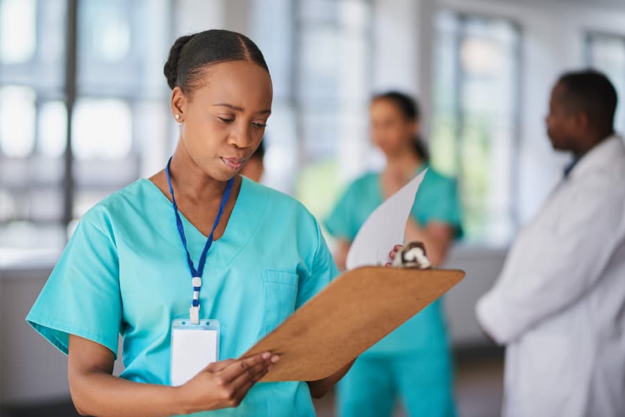 Nurse in scrubs holding clipboard