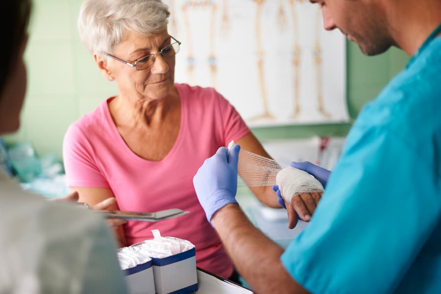 Practical nurse dressing an older patient’s wound