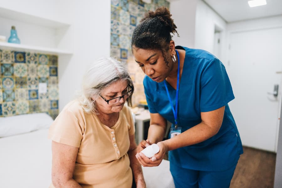 Practical nurse explaining to patient how to take medication 