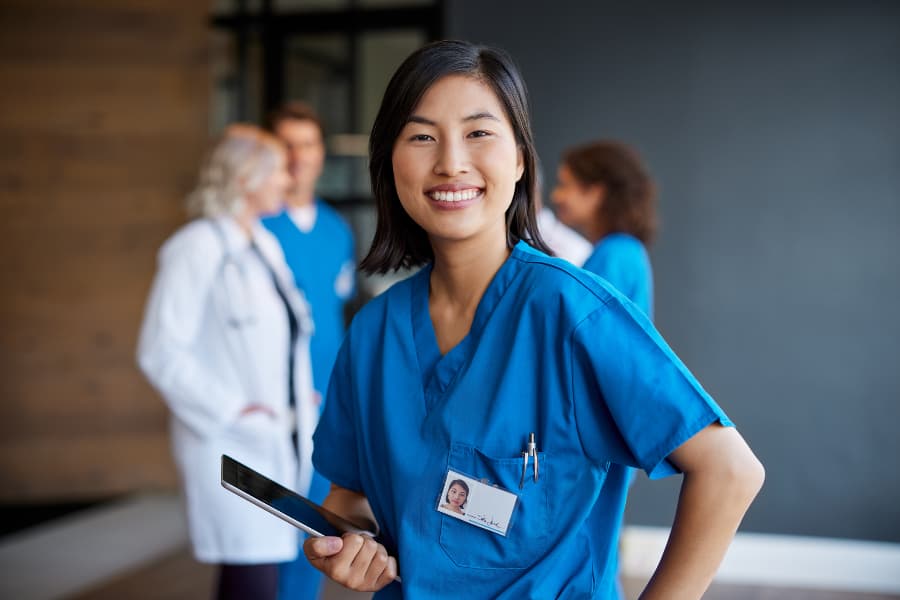 Nurse holding digital tablet with healthcare team in the background