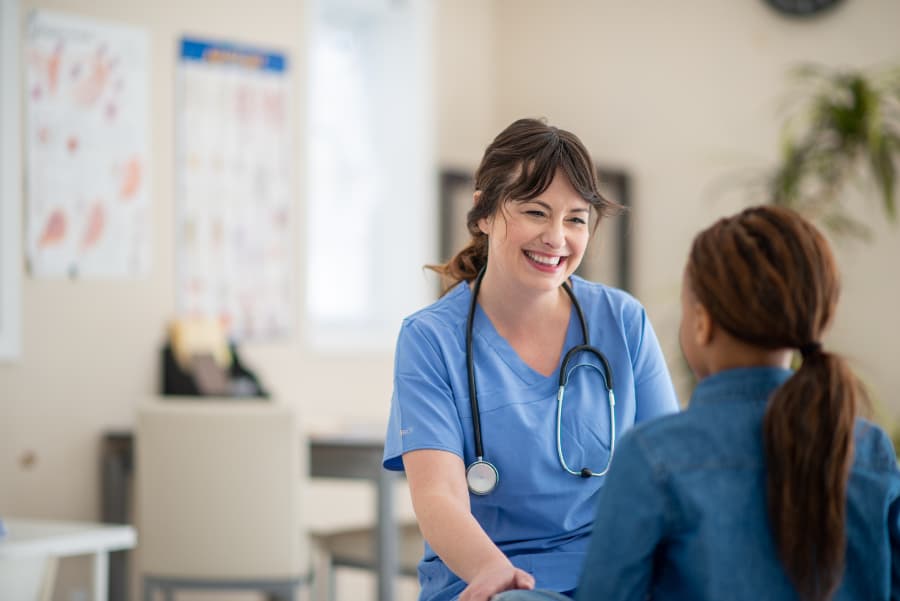 Smiling nurse talking with patient in clinic setting 