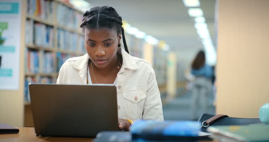 Young adult student looking at computer in library