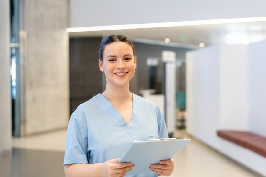 Happy nurse with patient health report in hospital holding clipboard 