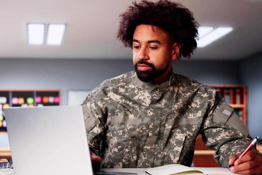 Military veteran in camo using laptop to complete schoolwork