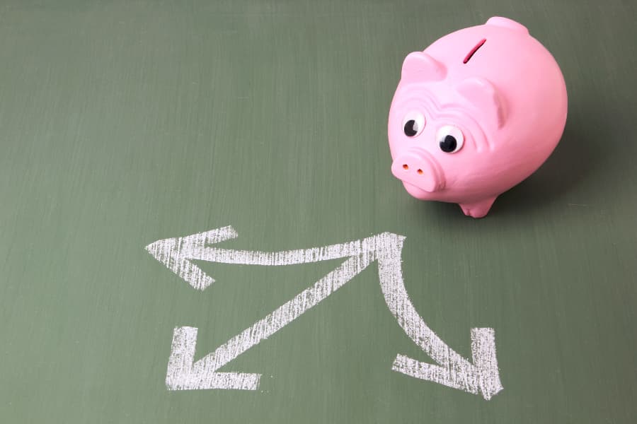 Piggy bank standing in front of three arrows showing different directions