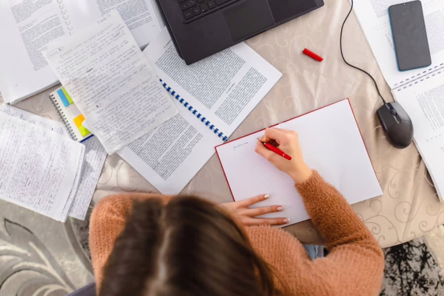Student studying with notes and laptop at home