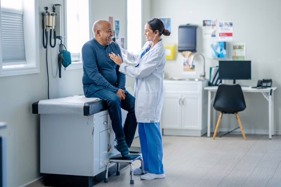 Medical professional listening to patient’s heart with stethoscope in doctor’s office