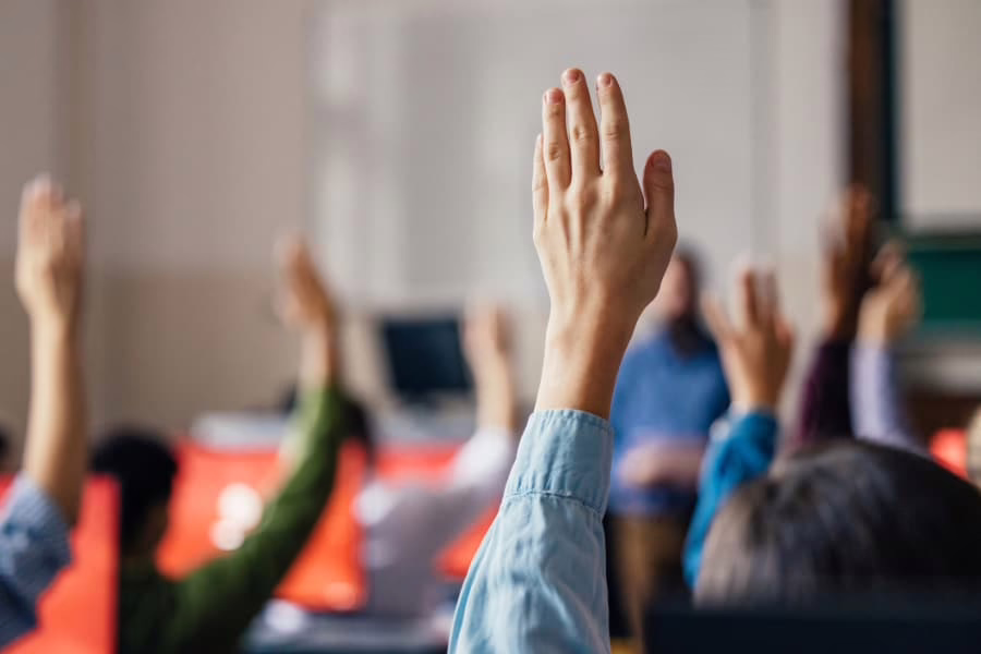 Students hands raised in classroom setting